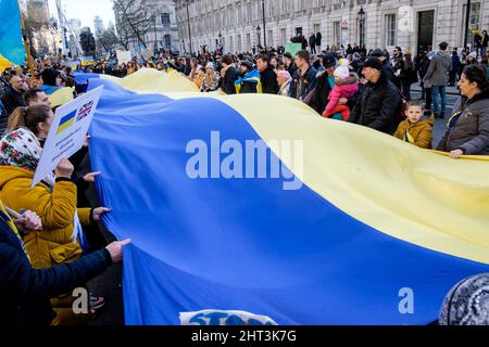 26.. Februar 2022: Ukrainische Staatsbürger und pro-ukrainische Anhänger versammeln sich in Whitehall, um gegen die russische Invasion in der Ukraine zu protestieren. London, Großbritannien. Im Bild: Bei der Demonstration in London wird ein langes Banner in den Farben der ukrainischen Flagge entrollt und hochgehalten. Stockfoto