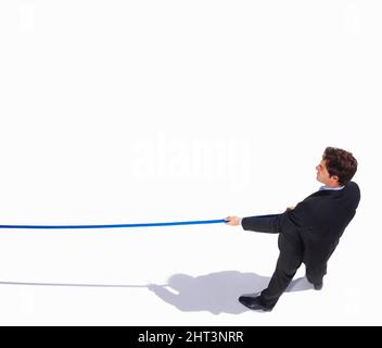 Draufsicht auf einen isolierten Geschäftsmann, der an einem Seil zieht. Tauziehen - Draufsicht auf einen jungen Geschäftsmann, der an einem Seil zieht. Stockfoto