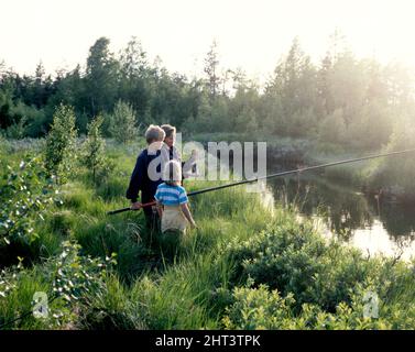 Kinder angeln am Bach in der Abendsonne Stockfoto