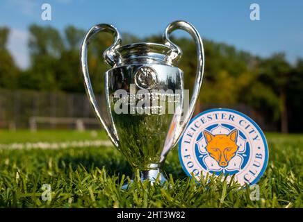 30. August 2021, Leicester, Großbritannien. Leicester City FC Fußballverein-Emblem und der UEFA Champions League Cup auf dem grünen Rasen des Stadions. Stockfoto