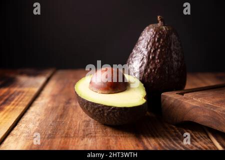 Mexikanische Avocado (Persea americana) auf rustikalem Holztisch. Hauptbestandteil zur Zubereitung von Guacamole. Nahaufnahme des Bildes Stockfoto