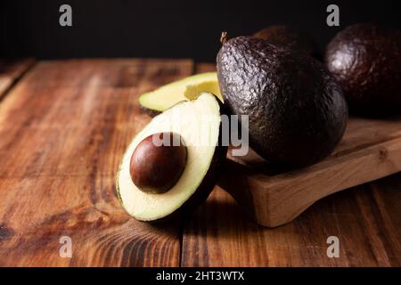 Mexikanische Avocado (Persea americana) auf rustikalem Holztisch. Hauptbestandteil zur Zubereitung von Guacamole. Nahaufnahme des Bildes Stockfoto