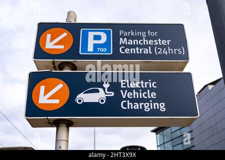 Manchester UK Richtungsschild für Parkplatz und Ladestation für Elektrofahrzeuge mit Logos Stockfoto