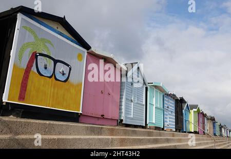 Eine Reihe von bunten Strandhütten am Meer in Walton on the Naze, Essex, beliebt bei Urlaubern auf dem Urlaub und Tagesausflüglern an der Küste. Stockfoto