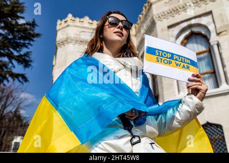 Istanbul, Türkei. 26.. Februar 2022. Eine Frau hält ein Schild mit der Aufschrift „Stoppt Putin, Stoppt den Krieg“ während eines Antikriegsproteste gegen die russische Invasion der Ukraine auf dem Beyazit-Platz in der Nähe der Universität Istanbul in Istanbul, Türkei. Am dritten Tag des Konflikts versammelten sich Hunderte, um gegen den Krieg zu protestieren. (Foto von Nicholy Muller/SOPA Images/Sipa USA) Quelle: SIPA USA/Alamy Live News Stockfoto