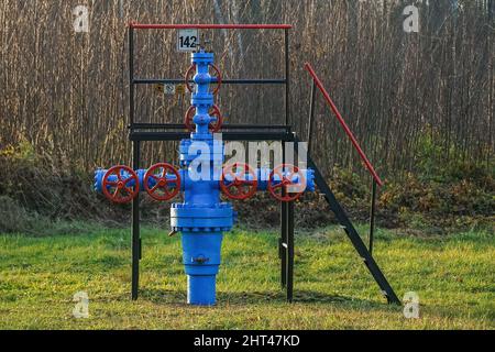 Blaue Brunnen Armaturen mit roten Ventilen in einem Gasbrunnen Stockfoto