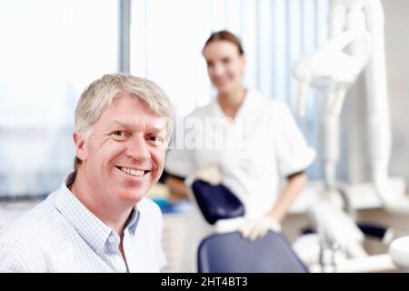 Lächelnder Arzt mit Assistent. Porträt eines hübschen Zahnarztes, der lächelt und seinen Assistenten im Büro hat. Stockfoto