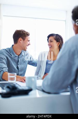 Glückliches Paar, das mit dem Berater diskutiert. Porträt eines glücklichen Paares, das beim Gespräch mit dem Finanzberater lacht. Stockfoto