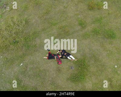 Draufsicht auf zwei Menschen, die auf grünem Gras liegen Stockfoto