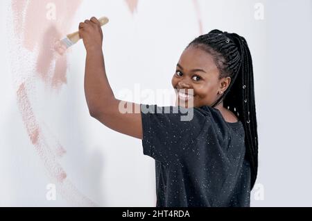 Nichts verleiht Ihrem Haus Persönlichkeit wie eine bunte Farbe Job. Aufnahme einer jungen Frau, die eine rosafarbene Wand malte. Stockfoto