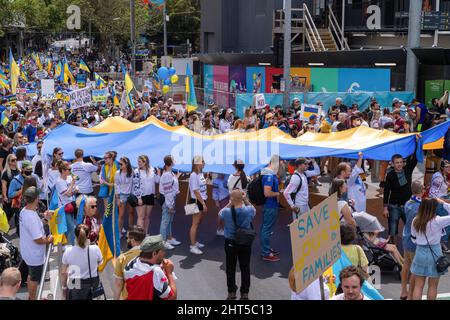 Melbourne, Australien, 27. Februar 2022. Eine Menge trägt eine große ukrainische Flagge während eines Protestes zur Unterstützung des Volkes und der Regierung der Ukraine angesichts einer russischen Invasion. Die Redner beteten und forderten die Lieferung von Waffen an die Ukraine und die Intervention der NATO und der Ungebundenen Nationen in Melbourne. Quelle: Michael Currie/Speed Media/Alamy Live News Stockfoto