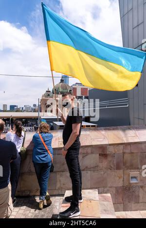 Melbourne, Australien, 27. Februar 2022. Ein Mann hält eine ukrainische Flagge während eines Protestes zur Unterstützung des Volkes und der Regierung der Ukraine angesichts einer russischen Invasion. Die Redner beteten und forderten die Lieferung von Waffen an die Ukraine und die Intervention der NATO und der Ungebundenen Nationen in Melbourne. Quelle: Michael Currie/Speed Media/Alamy Live News Stockfoto