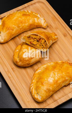 Argentinische hausgemachte Empanadas, gefüllt mit Huhn auf einem Holzbrett. Nahaufnahme. Stockfoto