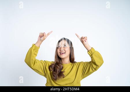 Schöne asiatische Frau in grünen T-Shirt zeigt die Finger nach oben Stockfoto