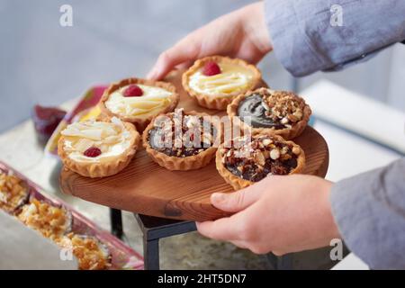 Sie wird zum Ausstellen des Backens gebracht. Eine Frau, die eine frische Portion Desserts ausgestellt hat, hat eine kurze Aufnahme gemacht. Stockfoto