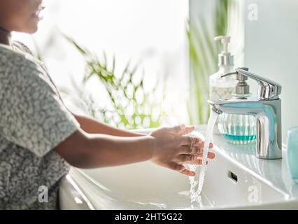 Saubere Hände sind Hüter der Gesundheit vor allem für Kinder. Nahaufnahme eines nicht erkennbaren Jungen, der sich in einem Badezimmer zu Hause am Wasserhahn die Hände wascht. Stockfoto