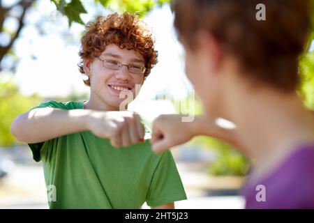 Beste Knospe. Kurzer Schuss von zwei Jungen im Teenageralter, die mit der Faust auf die Straße stoßen. Stockfoto