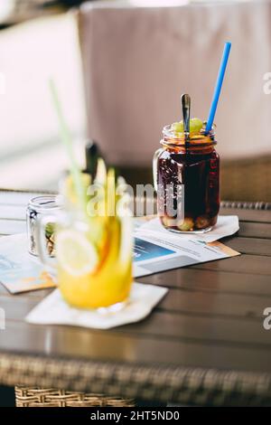 Vertikale Aufnahme von fertigen Limonaden mit Mango- und Traubengeschmack an der Bar. Stockfoto
