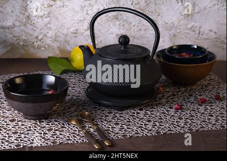 Ein Teetisch mit einem schwarzen Keramikkessel und Tassen darauf. Stockfoto