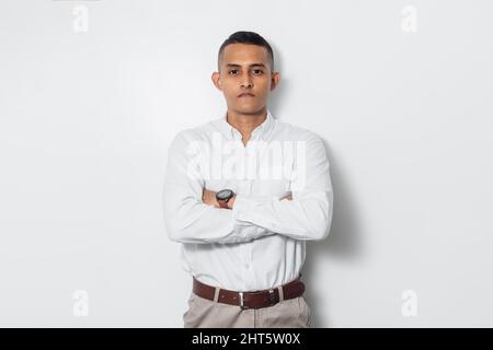Ein lateinamerikanischer Geschäftsmann, der ein Hemd mit der weißen Wand im Hintergrund trägt Stockfoto