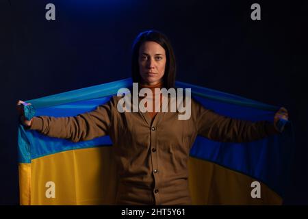 Traurige Frau mit ukrainischer Flagge. Konzept des Stehens mit der ukrainischen Nation im Krieg mit Russland. Stockfoto