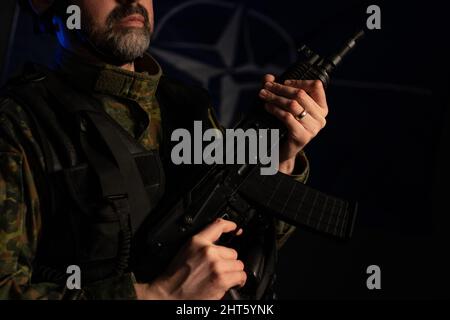 Nahaufnahme eines Soldaten in Militäruniform mit Waffe auf schwarzem Hintergrund. Stockfoto