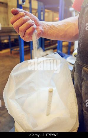 Hand gießen körnig auf Plastiktüte Nahaufnahme Stockfoto