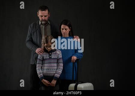 Flüchtlingsfamilie mit einem Kind, das auf schwarzen Hintergrund herunterschaut, Ukraine-Kriegskonzept. Stockfoto