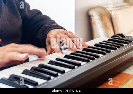 Ältere männliche Hände spielen ein musikalisches Keyboard, Synthesizer Stockfoto