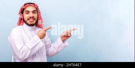Junger Mann mit Keffiyeh über isoliertem Hintergrund, der mit dem Finger zur Seite zeigt Stockfoto