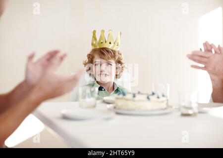 Der König liebt die Aufmerksamkeit. Aufnahme von zwei Personen, die sich für den Geburtstagsjungen in die Hände klatschen. Stockfoto