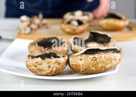 Champignon Pilze Kochvorgang. Rohe Portobello auf dem Teller. Gefüllte portobello Pilze Kochvorgang. Vegetarische Gerichte Stockfoto