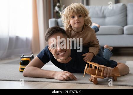 Portrait von fröhlichen Vater hält auf dem Rücken niedlichen Sohn. Stockfoto