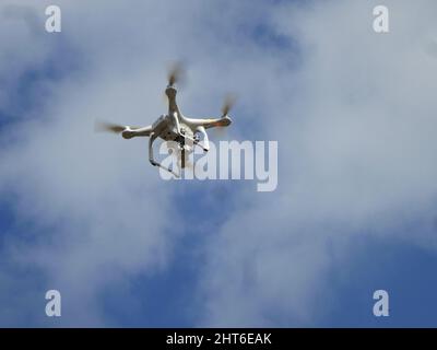 Kamera-Drohne, die hoch in den bewölkten Himmel fliegt Stockfoto