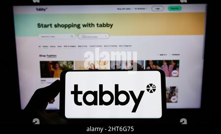 Person, die das Smartphone mit dem Logo des arabischen Finanzunternehmens Tabby FZ LLC auf dem Bildschirm vor der Website hält. Konzentrieren Sie sich auf die Telefonanzeige. Stockfoto