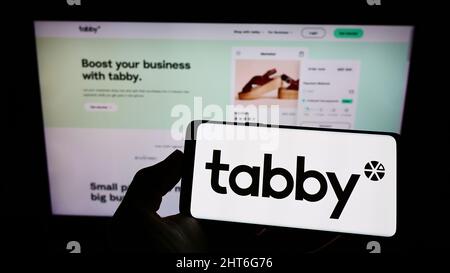 Person, die Mobiltelefon mit dem Logo des arabischen Finanzunternehmens Tabby FZ LLC auf dem Bildschirm vor der Business-Webseite hält. Konzentrieren Sie sich auf die Telefonanzeige. Stockfoto
