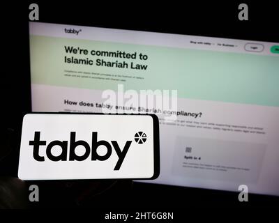Person, die Mobiltelefon mit dem Logo des arabischen Finanzunternehmens Tabby FZ LLC auf dem Bildschirm vor der Business-Webseite hält. Konzentrieren Sie sich auf die Telefonanzeige. Stockfoto