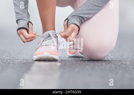 Konzentrieren Sie sich auf Ihr Endziel. Nahaufnahme einer nicht erkennbaren Person, die ihre Schnürsenkel beim Training bindet. Stockfoto