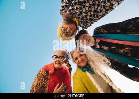 Direkt unter der Aufnahme exzentrischer älterer Menschen, die die Kamera im Freien betrachten. Eine Gruppe von sorglosen Senioren in farbenfroher Freizeitkleidung. S Stockfoto