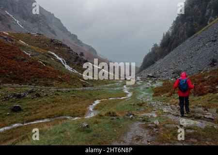 Wanderer, die an einem nassen, regnerischen Tag den Broadslack Gill in voller Fahrt auf dem Castle Crag Walk entlang gehen, Lake District, Cumbria, England, VEREINIGTES KÖNIGREICH Stockfoto