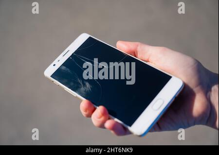 Frau hält Smartphone mit defekten Bildschirm im Freien. Stockfoto