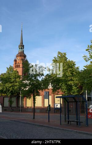 Blick auf Itzehoe Stadtbild im Sommer mit St. Laurentii Kirche Uhrenturm und blauen Sonnenuntergang Himmel Hintergrund. Bushaltestelle im Vordergrund. Keine Personen. Stockfoto