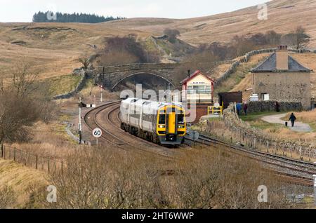 Ein Sprinter-Personenzug fährt auf der berühmten Selle-Carlisle-Bahn von Carlisle aus an der abgelegenen Blea Moor-Signalbox nach Leeds vorbei. Stockfoto