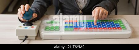 Frau mit zerebraler Lähmung arbeitet an einer spezialisierten Computermaus. Stockfoto