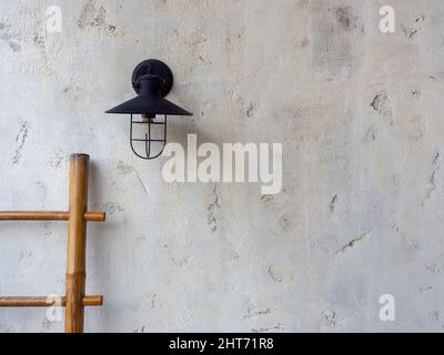 Leerer Raum aus weißem Beton Wandstruktur Hintergrunddekoration mit Wandlampe und hölzerner Bambusleiter. Stockfoto