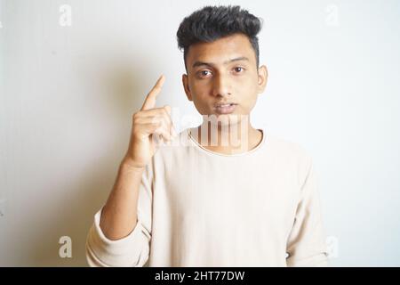 Ein indischer Mann, der auf einen weißen Hintergrund zeigt Stockfoto