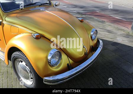 Vorderseite des goldfarbenen Volkswagen-Käferwagens auf der Straße in den Niederlanden Stockfoto