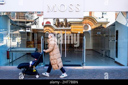 Epsom Surrey UK, Februar 27 2022, Frau mit Kinderwagen, die nach der Covid-Pandemie an Einem geschlossenen und leeren Einzelhandelsgeschäft in der High Street vorbeiläuft Stockfoto