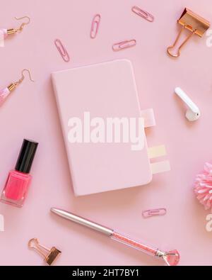 Hardcover-Notizbuch und rosa Schulzubehör auf pastellrosa, Draufsicht, Textbuch-Modell. Girly Arbeitsplatz mit Schere, Bleistifte, Stift, Büroklammern, Ohr Stockfoto