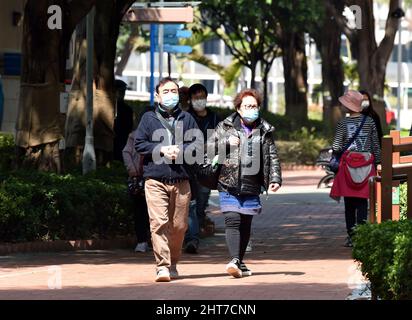 Hongkong, China. 27.. Februar 2022. Maskierte Menschen gehen in Hongkong, Südchina, auf der Straße, 27. Februar 2022. Hongkong meldete am Sonntag 26.026 neue COVID-19-Fälle, offizielle Daten zeigten. Quelle: Lo Ping Fai/Xinhua/Alamy Live News Stockfoto